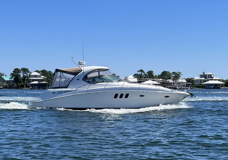 The Image of A white 2006 Sea Ray 380 Sundancer boat cruising on calm water, surrounded by houses. - 1