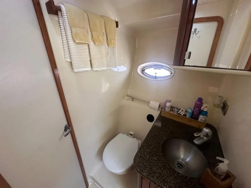 Slide: The Image of Bathroom in a 2006 Sea Ray 380 Sundancer with sink, toilet, and towels. - 14