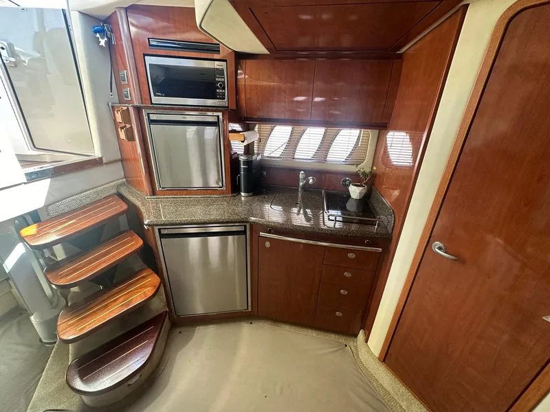 Slide: The Image of The 2006 Sea Ray 380 Sundancer's galley features wood cabinets, a sink, and stainless steel appliances. - 6