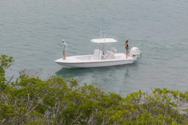 Slide: The Image of 2027 Contender 26 Bay boat with two people fishing in calm waters near greenery. - 4