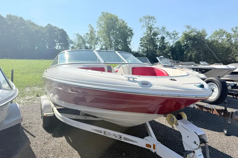 Slide: The Image of 2006 Sea Ray 210 Bow Rider boat on trailer, red and white design, parked outdoors. - 2