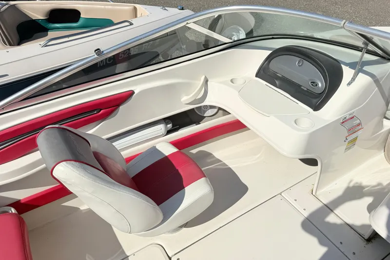 Slide: The Image of 2006 Sea Ray 210 Bow Rider interior with red and white seating, dashboard, and steering wheel. - 6