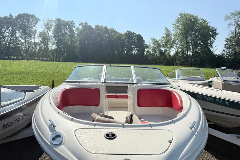 Slide: The Image of 2006 Sea Ray 210 Bow Rider boat with red seating, parked outdoors on a sunny day. - 3