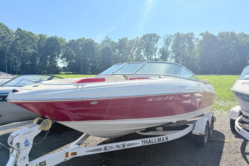 The Image of 2006 Sea Ray 210 Bow Rider boat on trailer, parked outdoors under clear sky. - 1
