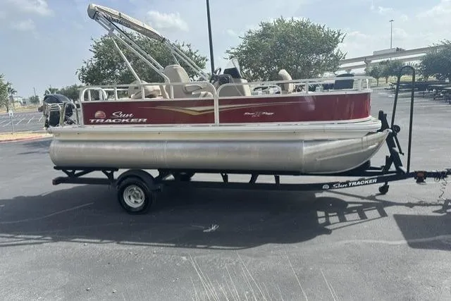 Slide: The Image of 2025 Sun Tracker Bass Buggy 18 DLX pontoon boat on trailer in parking lot. - 11