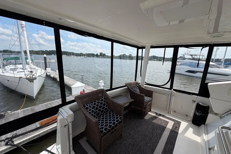 Slide: The Image of 2002 Silverton 392 Motor Yacht interior with wicker chairs, overlooking marina and sailboats. - 9