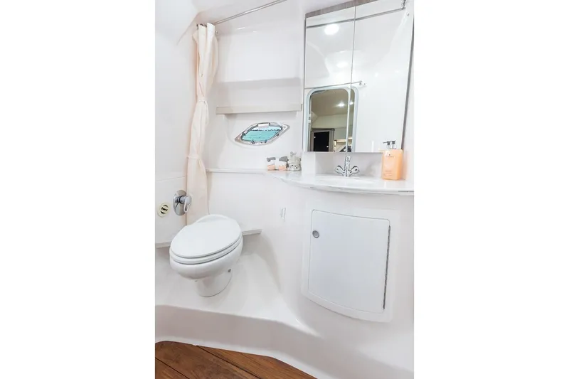 Slide: The Image of Manufacturer Provided Image: 2019 Regal 35 Sport Coupe bathroom with toilet, sink, mirror, and porthole window. - 14
