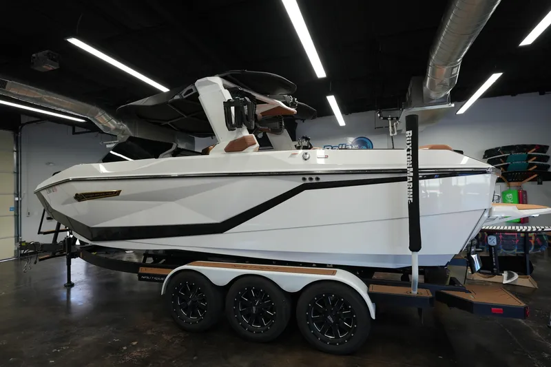 The Image of 2025 Nautique Super Air Nautique G23 boat on trailer in showroom, side view. - 1