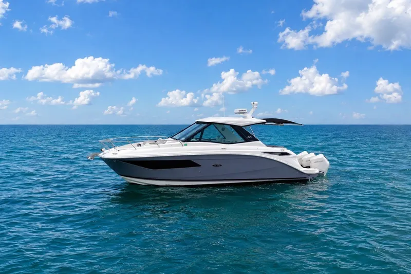 The Image of 2022 Sea Ray Sundancer 320 Coupe Outboard cruising on open ocean under blue sky. - 0