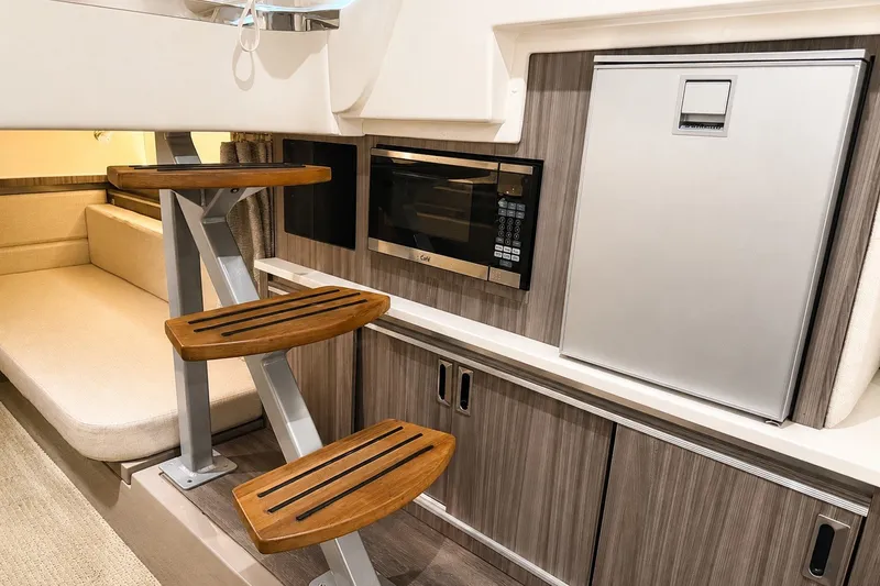 Slide: The Image of Interior of 2022 Sea Ray Sundancer 320 Coupe Outboard with modern kitchenette and wooden steps. - 32