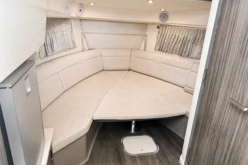 Slide: The Image of 2022 Sea Ray Sundancer 320 Coupe Outboard cabin interior with beige seating and wood accents. - 35