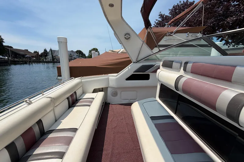 Slide: The Image of 1989 Sea Ray Sundancer 280 interior with striped seating, docked by waterfront homes. - 13