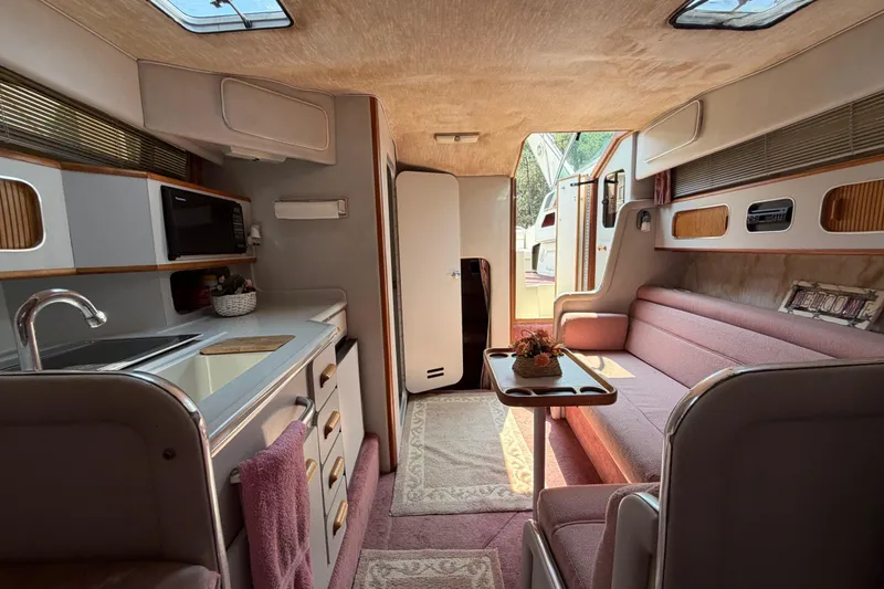 Slide: The Image of Interior of a 1989 Sea Ray Sundancer 280, featuring a cozy seating area and kitchenette. - 30