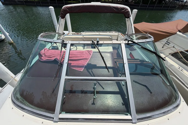 Slide: The Image of 1989 Sea Ray Sundancer 280 boat with windshield and pink towel, docked by the water. - 6