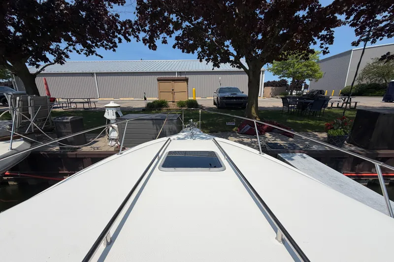 Slide: The Image of 1989 Sea Ray Sundancer 280 docked, view from bow, trees and building in background. - 5