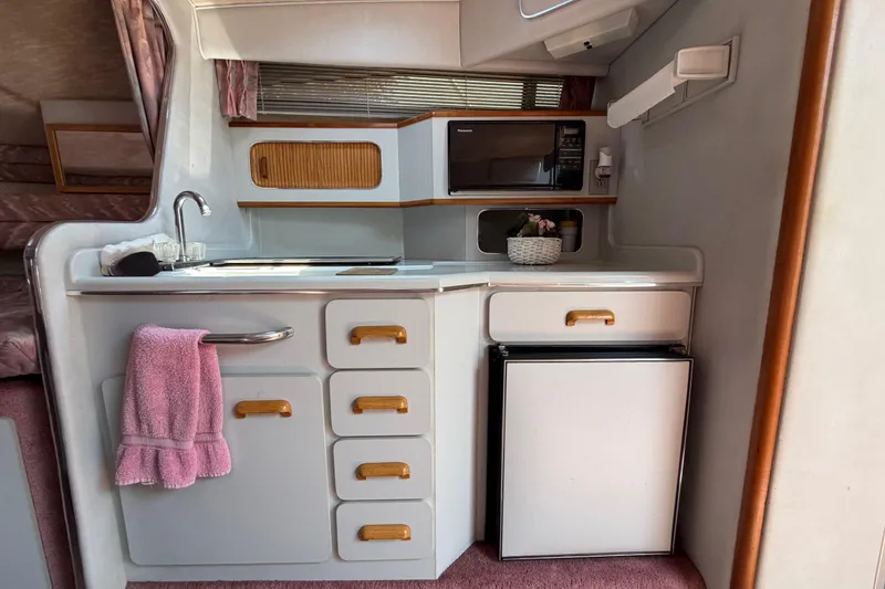 Slide: The Image of 1989 Sea Ray Sundancer 280 interior kitchen with sink, microwave, and mini fridge. - 24