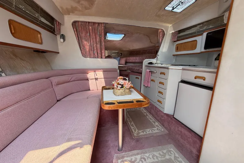 Slide: The Image of Interior of a 1989 Sea Ray Sundancer 280 with pink seating and compact kitchen area. - 23
