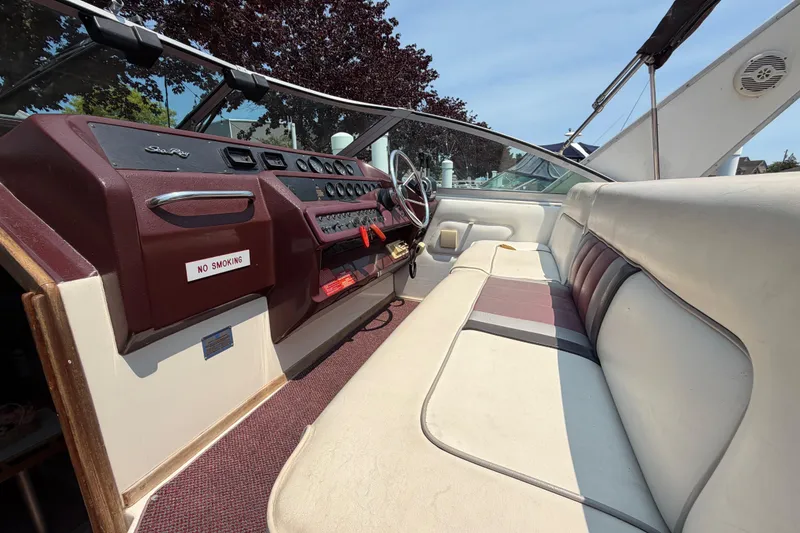 Slide: The Image of 1989 Sea Ray Sundancer 280 cockpit with maroon dashboard, steering wheel, and beige seating. - 16