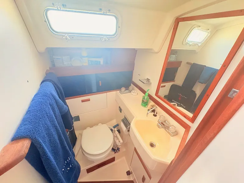 Slide: The Image of The image shows a boat bathroom with a toilet, sink, and mirror. - 19