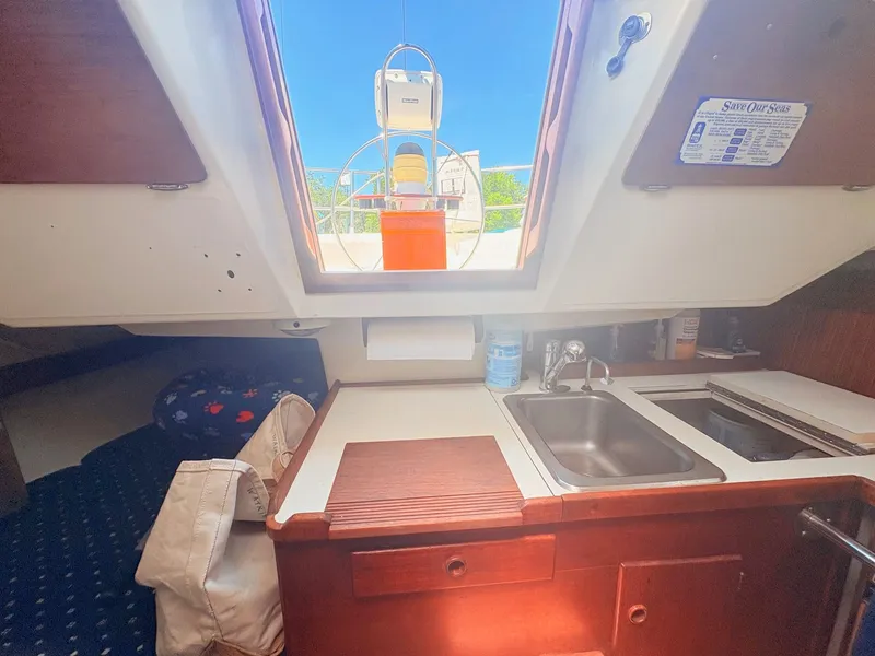 Slide: The Image of Interior view of a sailboat with sink, wooden countertop, and skylight. The helm is visible in the background. - 15