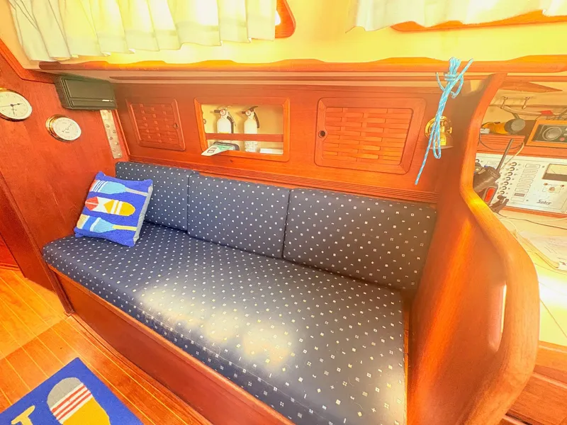 Slide: The Image of The image shows the interior of a 1987 Sabre 30 MK III. A cushioned sofa with blue pillows is set against a wooden wall with built-in cabinets. - 12