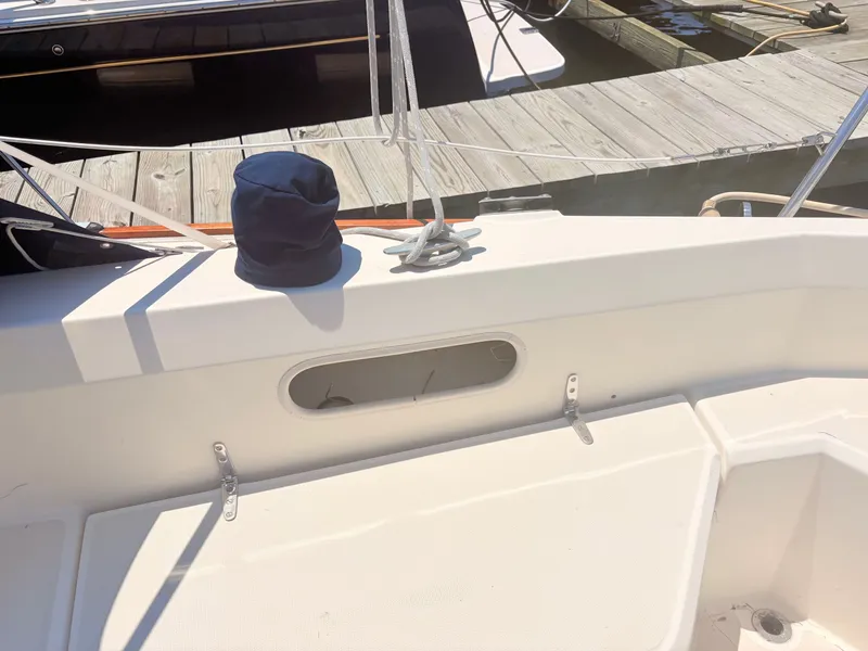 Slide: The Image of A sailboat with a blue hat on the deck, moored at a wooden dock. - 33