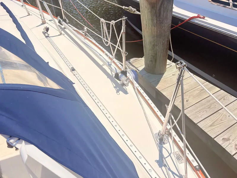 Slide: The Image of The deck of a sailboat with blue covers and ropes attached to a wooden post. - 34