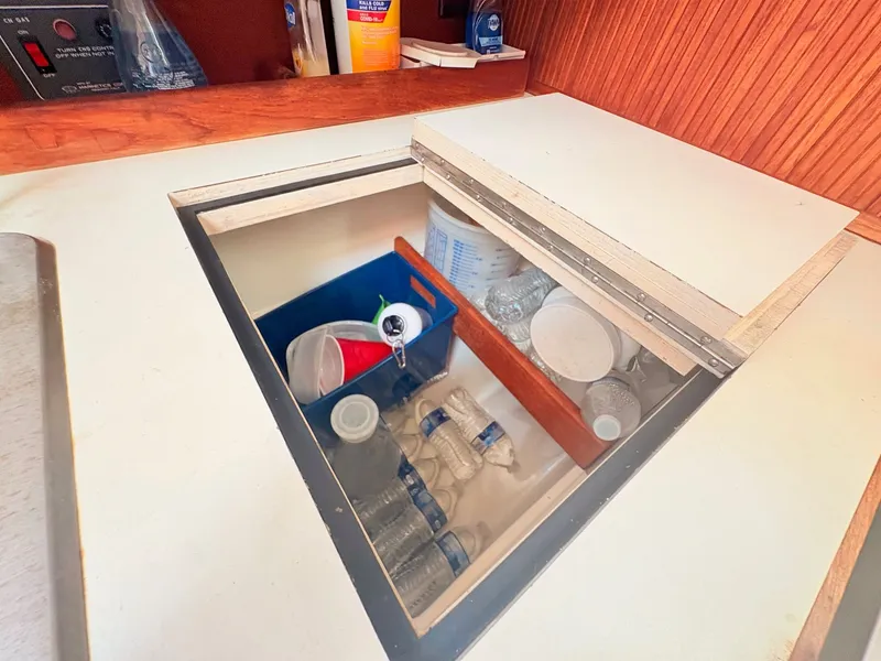 Slide: The Image of An open storage compartment in a boat galley with water bottles and cleaning supplies. - 31