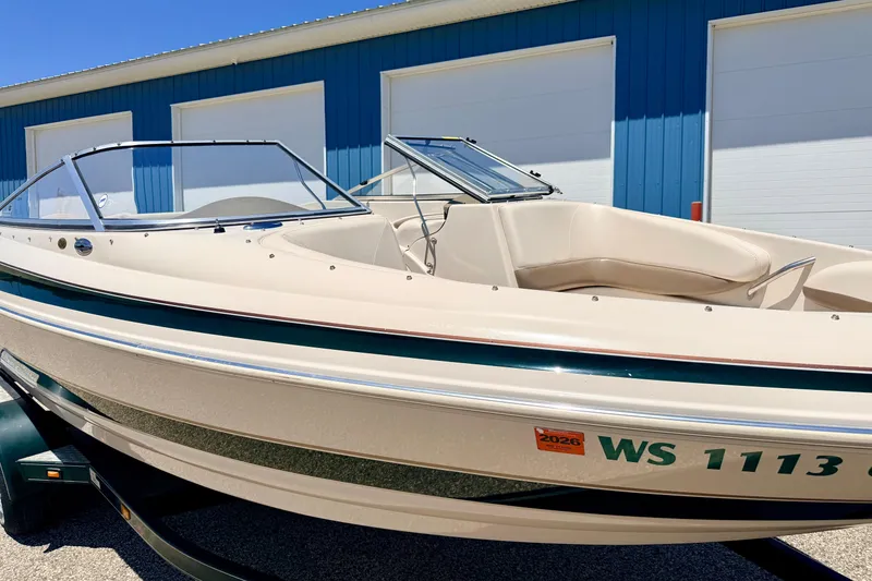 Slide: The Image of 2002 Larson LXi 210 boat with beige exterior, parked near blue building. - 8