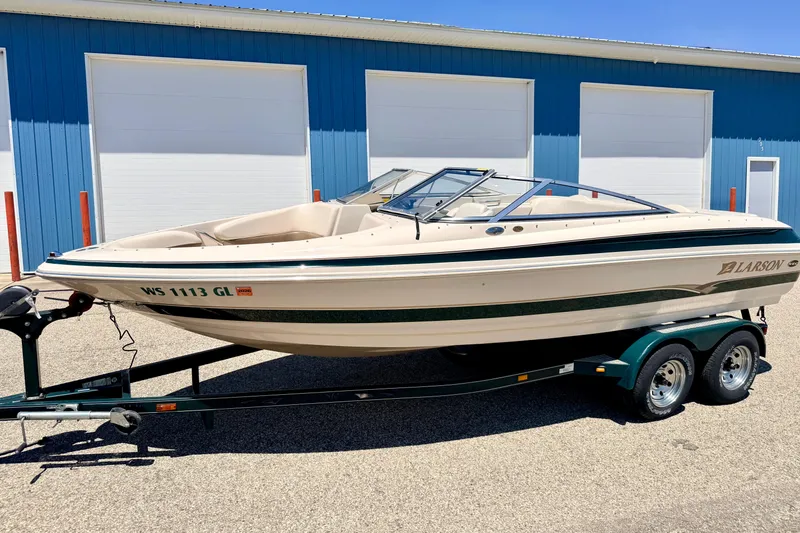 Slide: The Image of 2002 Larson LXi 210 boat on trailer, parked outside blue building. - 4