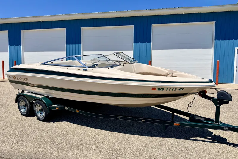 The Image of 2002 Larson LXi 210 boat on trailer, parked outside blue storage units. - 1