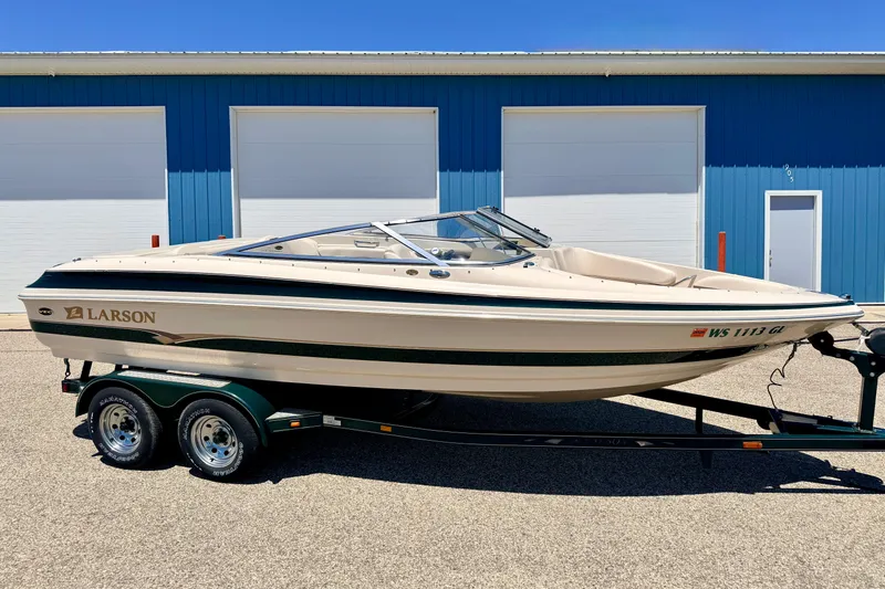Slide: The Image of 2002 Larson LXi 210 boat on trailer, parked in front of blue building. - 3