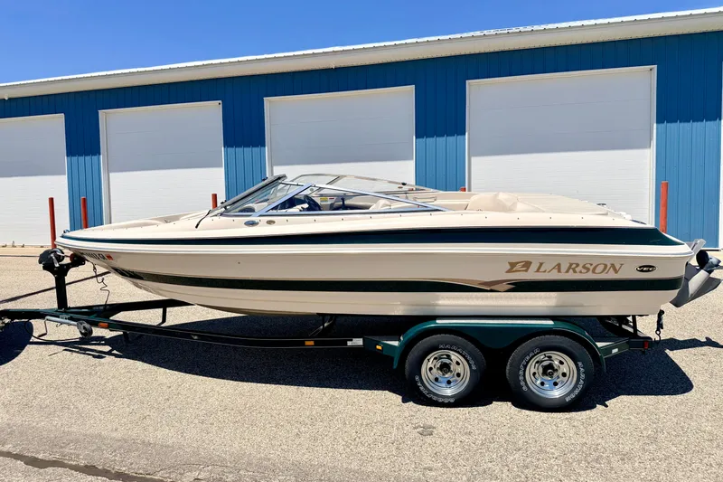 Slide: The Image of 2002 Larson LXi 210 boat on trailer, parked outside blue garage doors. - 6