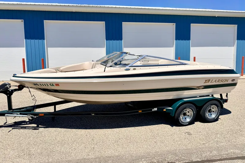 Slide: The Image of 2002 Larson LXi 210 boat on trailer, parked outside blue garage doors. - 2