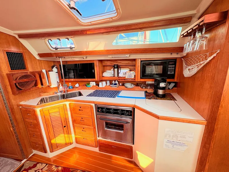 Slide: The Image of The galley of a 1994 Catalina 42 with wooden cabinets, stove, sink, and microwave. - 21