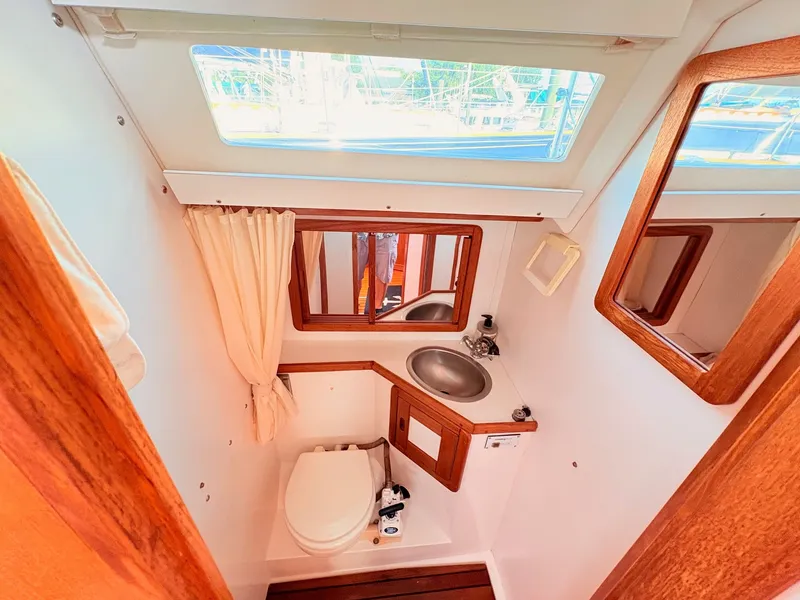 Slide: The Image of The image shows the bathroom of a 1994 Catalina 42 with wood trim and a porthole. - 41