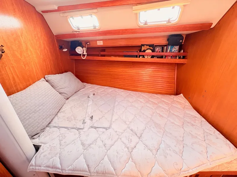 Slide: The Image of The cabin of a 1994 Catalina 42 featuring a cozy double bed and wooden walls. - 25