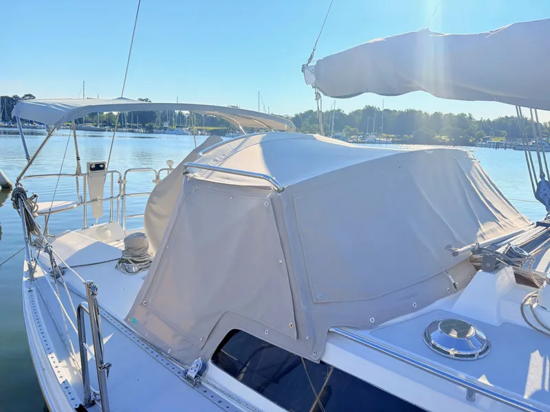 Slide: The Image of A 1994 Catalina 42 with a gray canopy, docked in calm harbor waters. - 2