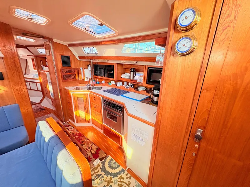 Slide: The Image of Interior of a 1994 Catalina 42 with wooden finishes and a well-equipped kitchen. - 18