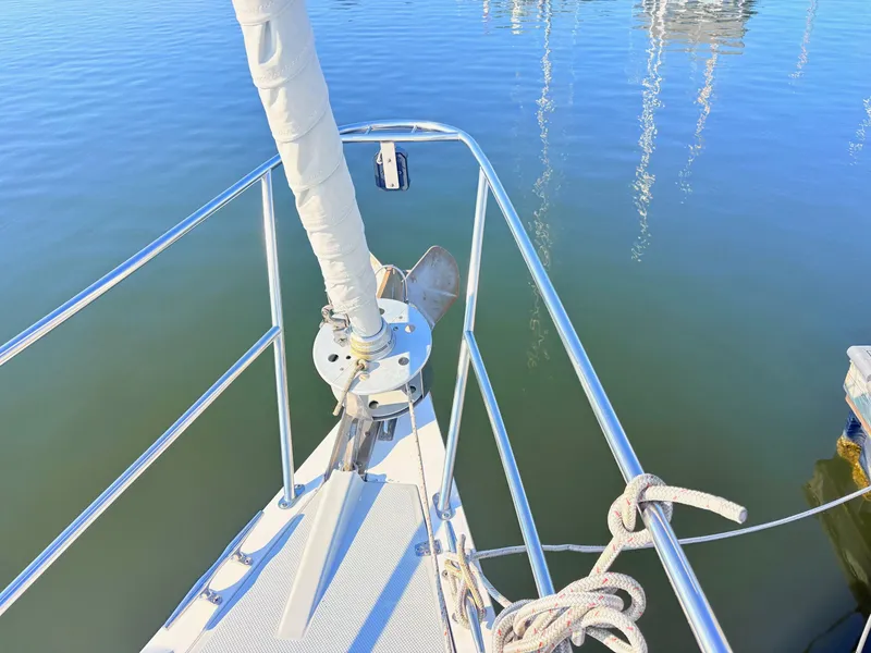 Slide: The Image of The bow of a 1994 Catalina 42 with anchor and ropes, resting on calm water. - 13