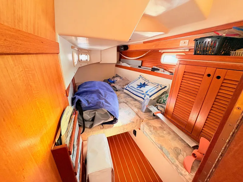 Slide: The Image of The cabin of a 1994 Catalina 42 with wood paneling and a cozy bed. - 33
