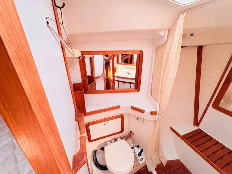 Slide: The Image of The image shows the bathroom of a 1994 Catalina 42 with wood paneling and a mirror. - 29