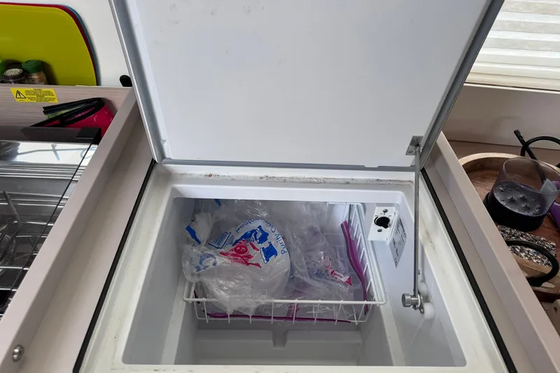 Slide: The Image of Freezer compartment on 2022 Beneteau Oceanis 46.1 yacht, containing ice bags and storage basket. - 50