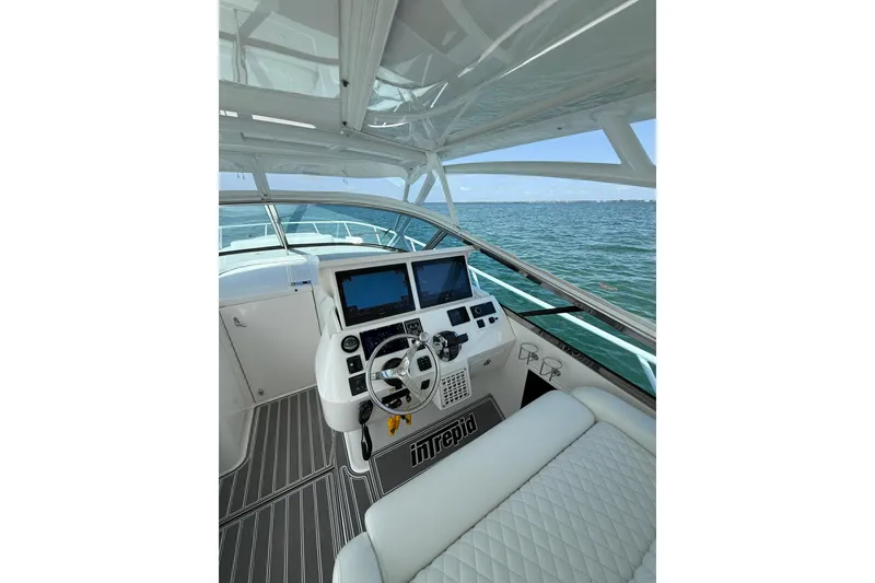 Slide: The Image of 2017 Intrepid 430 Sport Yacht helm with dual screens, steering wheel, and ocean view. - 32