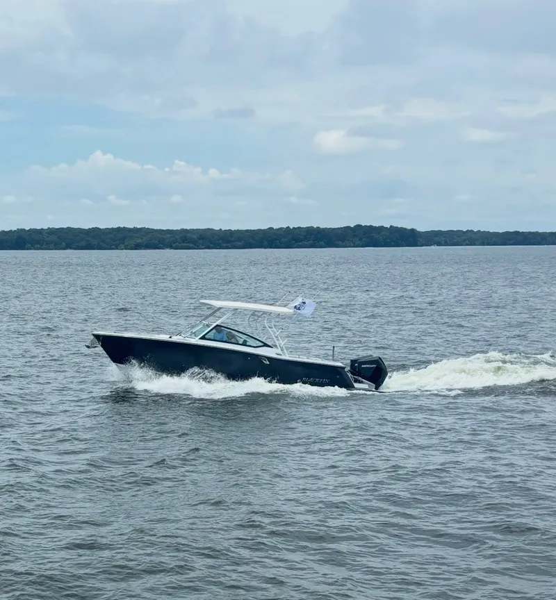 Slide: The Image of A 2024 Blackfin 272 DC boat cruising on calm waters under a cloudy sky. - 2