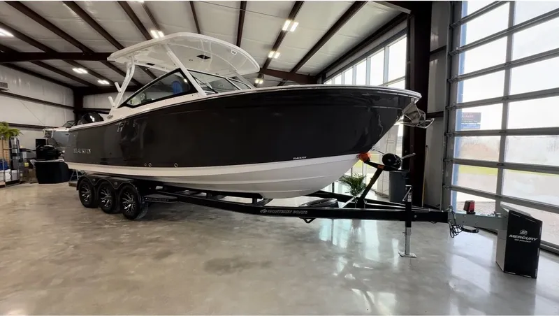 Slide: The Image of A 2024 Blackfin 272 DC boat on a trailer inside a warehouse. - 1