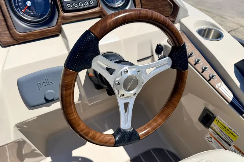 Slide: The Image of Steering wheel of 2015 Manitou 25 SES BENCH boat with wood accents and controls. - 48