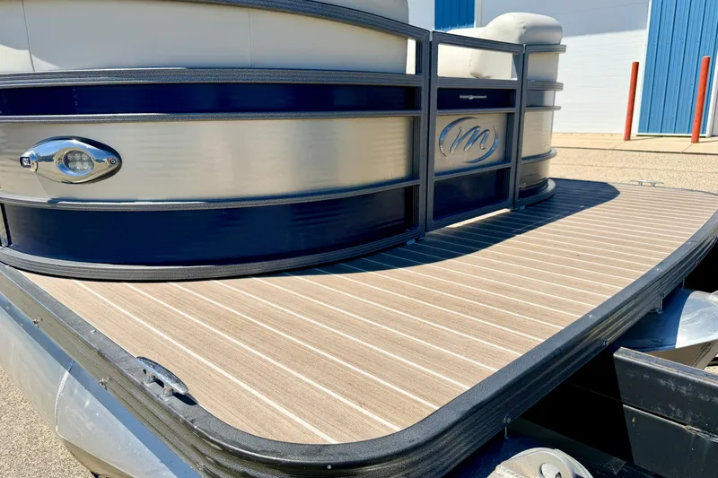 Slide: The Image of 2015 Manitou 25 SES BENCH pontoon boat with sleek design and wood-textured deck. - 90