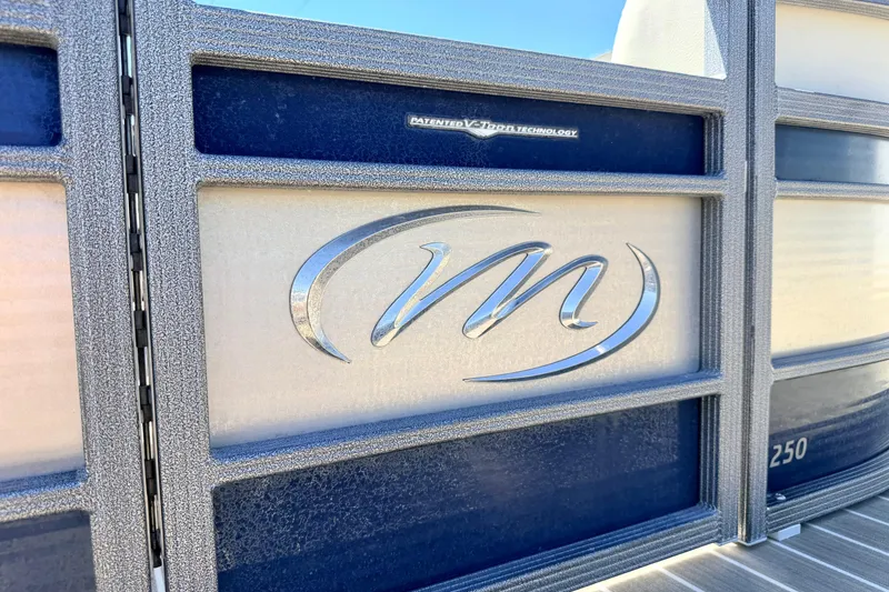 Slide: The Image of 2015 Manitou 25 SES BENCH boat with metallic logo and textured paneling. - 11