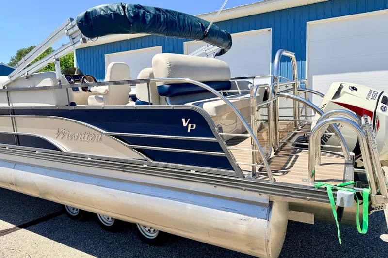 Slide: The Image of 2015 Manitou 25 SES BENCH pontoon boat with Evinrude engine, parked near blue building. - 9